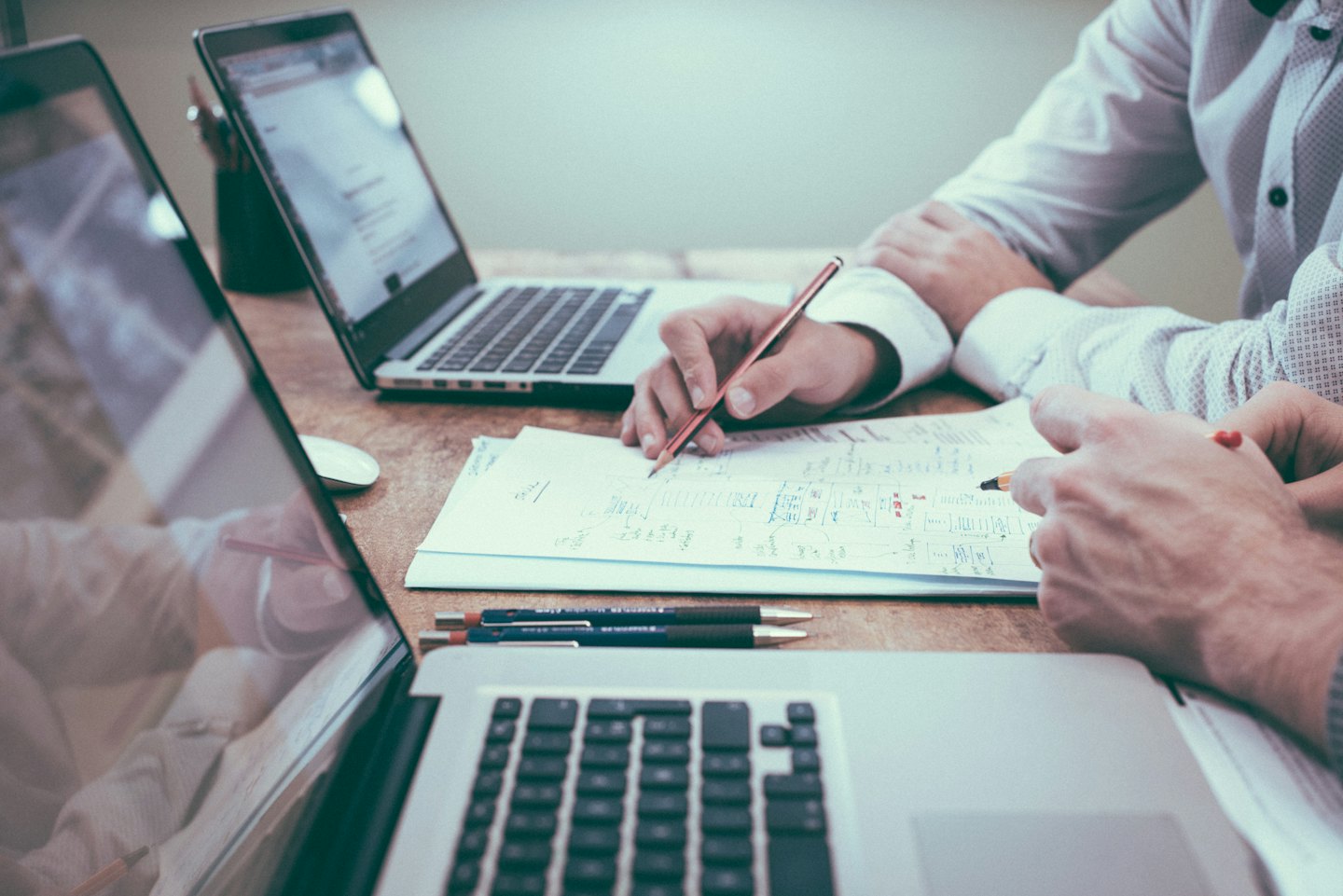 Dos profesionales colaborando sobre documentos y ordenadores portátiles.